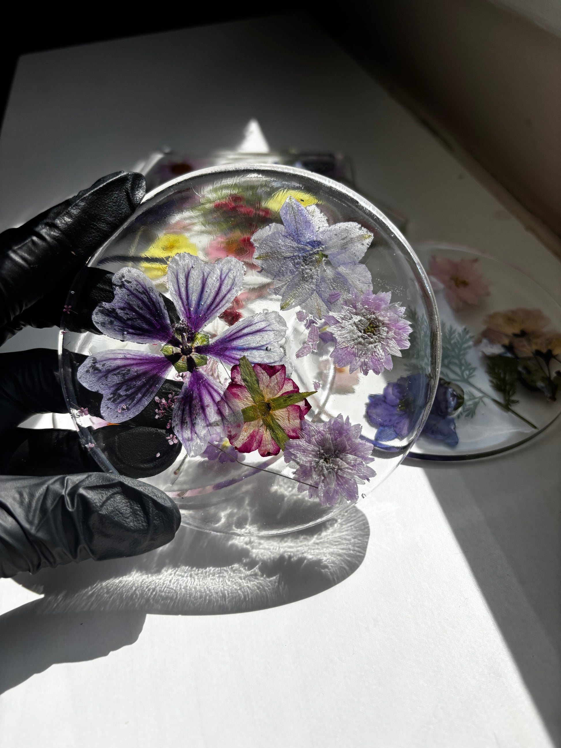 Transparent resin coaster with pressed flowers on a light surface