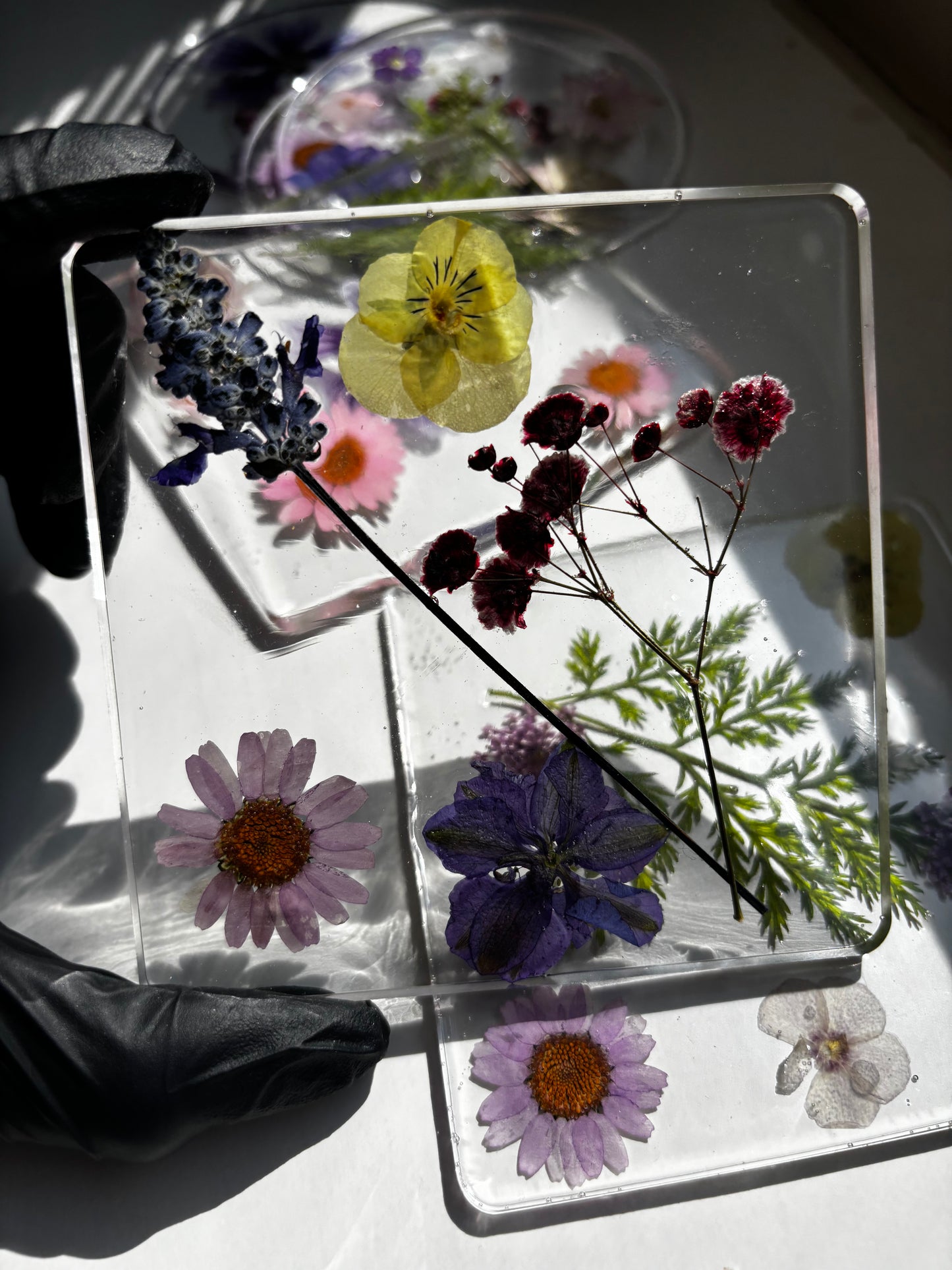 Transparent resin coaster with pressed flowers on a light surface